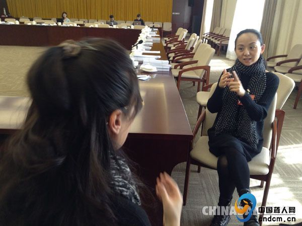 全国政协委员邰丽华（右）在她的手语翻译（左）的协助下与记者交流。